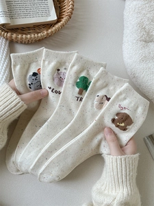 Dettaglio di calze in maglia beige con simpatici ricami cartoon 3D e puntini colorati