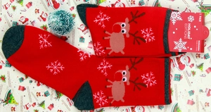 Close-up of red Christmas socks with reindeer and snowflake patterns in holiday packaging