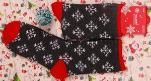 Close-up of grey Christmas socks with snowflake patterns and red contrasting toe and heel