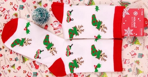 Detail of Christmas crew socks featuring reindeer and wreath patterns on a festive backdrop