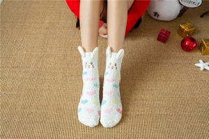 Close-up of white coral fleece socks featuring 3D rabbit ears and colorful heart patterns