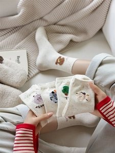 Dettaglio di ricami a cartone animato su calze in cotone puntinato color crema da donna