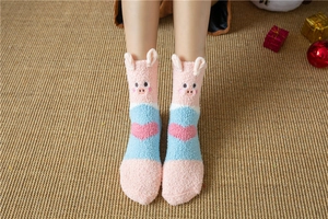Detail of pink coral fleece socks with 3D pig ears and heart pattern on straw mat