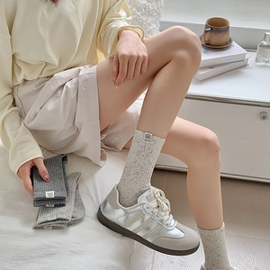 Detail of ribbed knit crew socks with logo patch shown with vintage sneakers