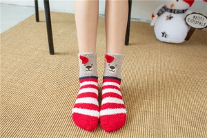Close-up of fluffy Christmas socks with bear face embroidery and festive red stripes