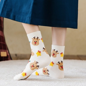 Cozy white cotton Christmas socks with reindeer and bell patterns worn by a person