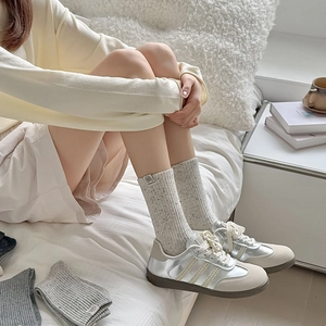Detail of grey vintage knit socks styled with metallic leather sneakers in a cozy setting