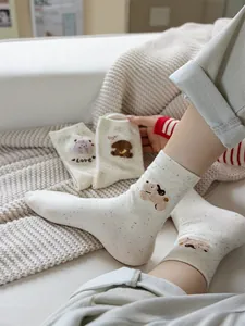 Dettaglio di ricamo a forma di orso su calze di cotone a metà polpaccio beige