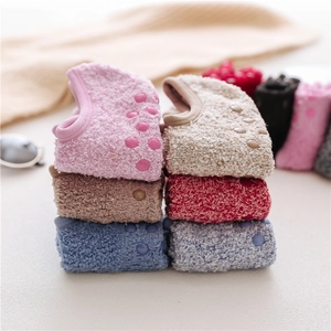 Close-up of non-slip silicone grips on warm coral fleece bow floor socks with plush texture