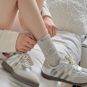 Close-up of retro speckled crew socks with cartoon dog patch and metallic fashion sneakers