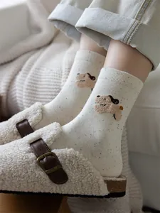 Dettaglio di calze in maglia a pois colorati con decorazione patch a forma di cane 3D