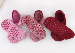 Close-up of non-slip grips on coral fleece slipper socks in three pink and red shades