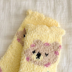 Detailed close-up of soft yellow coral fleece socks with cute koala embroidery