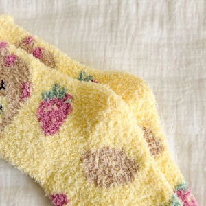 Close-up of yellow coral fleece socks with cute strawberry and brown bear patterns