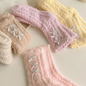 Close-up of thick coral fleece warm socks with silver ribbon bows in macaron colors