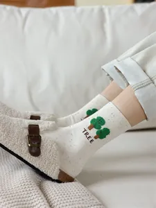 Dettaglio calzini in cotone bianco con pois colorati e motivo di albero verde