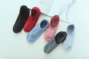 Close-up of soft coral fleece floor socks in six colors on a plush white surface
