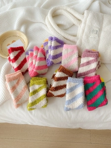 Flat lay of multiple colorful striped coral fleece winter socks on soft knit blanket
