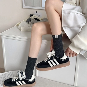 Close-up of retro dark grey flecked knit socks styled with black vintage sneakers