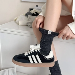 Close-up of retro grey speckled mid-calf socks with vintage fabric label and sporty sneakers