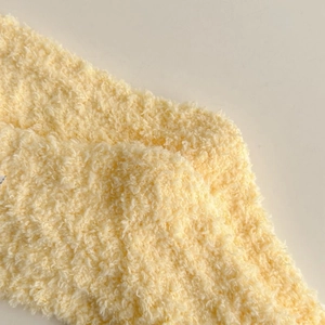 Macro shot of fluffy light yellow coral fleece fabric texture for warm thermal socks