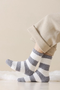 Close-up of thick grey and white striped coral fleece socks worn for home comfort