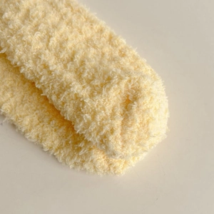 Close-up of soft yellow coral fleece socks showing thick plush texture and warm material