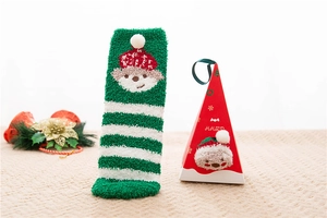 Detailed view of striped coral fleece Christmas socks with festive gift packaging box