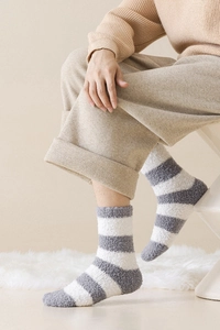 Detail of gray and white striped coral fleece thermal socks on a cozy carpet