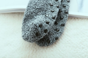 Close-up of gray thermal fuzzy socks with non-slip rubber dots on cozy carpet