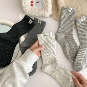 Close-up of retro ribbed knit socks with mottled texture and dog pattern woven label