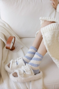 Detail of warm coral fleece striped socks and plush slippers for winter comfort