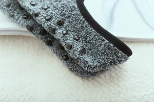 Detail of grey plush slipper socks featuring black non-slip silicone dots and neat edging