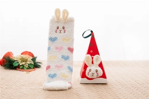 Close-up of fluffy white fleece socks with bunny ears and a red gift box set