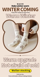 Detail of warm winter socks featuring cute brown cartoon bear patterns on creamy knit fabric