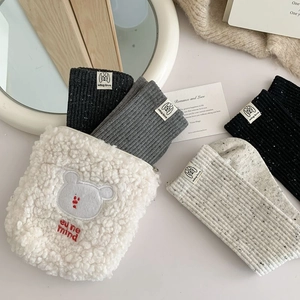 Close-up of ribbed knit socks and fuzzy embroidered bag in a stylish home setting