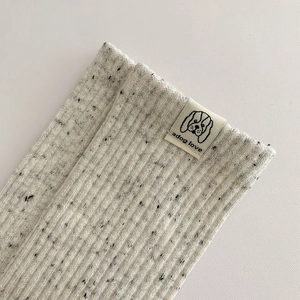 Close-up of light grey speckled ribbed cotton socks with minimalist adog love fabric label
