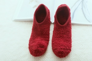 Deep red plush floor socks made of thick sherpa fleece on a soft white carpet
