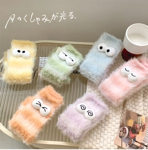 Close-up of fluffy coral fleece socks in pastel colors with cute cartoon eye patches