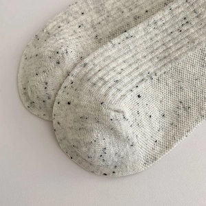 Macro detail of retro grey flecked knit socks featuring vertical ribbed texture and flat seams