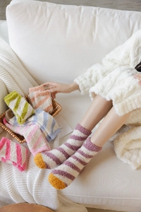Detailed view of colorful striped coral fleece warm socks in a cozy home setting