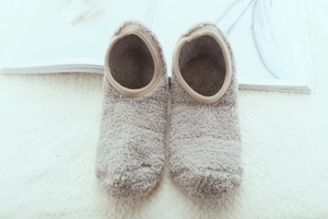 Detailed top view of cozy plush thermal slipper socks on a soft white fluffy carpet