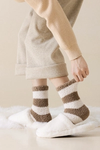 Detail of brown and white striped coral fleece socks worn with plush slippers