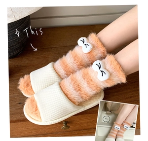 Detail of coral fleece striped socks with cute bow decoration and waffle slippers