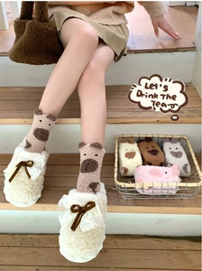 Détail de chaussettes ours en polaire corail et chaussons en peluche blanche à nœuds
