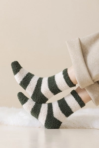 Close-up of green striped coral fleece socks worn on feet for winter warmth