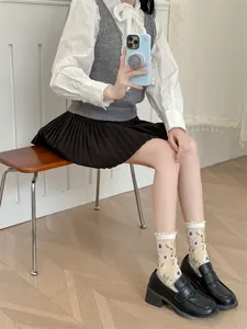 Détail de chaussettes en coton beige avec motifs floraux mauves et bordure en dentelle