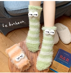 Close-up of thick coral fleece socks with 3D eyes and stripes for winter warmth