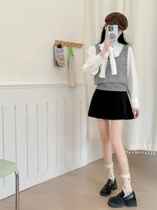 Détail de chaussettes à fleurs vintage portées avec mocassins noirs et jupe plissée