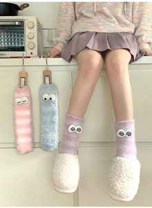 Close-up of soft coral fleece striped socks with cute 3D eyes and fuzzy white slippers